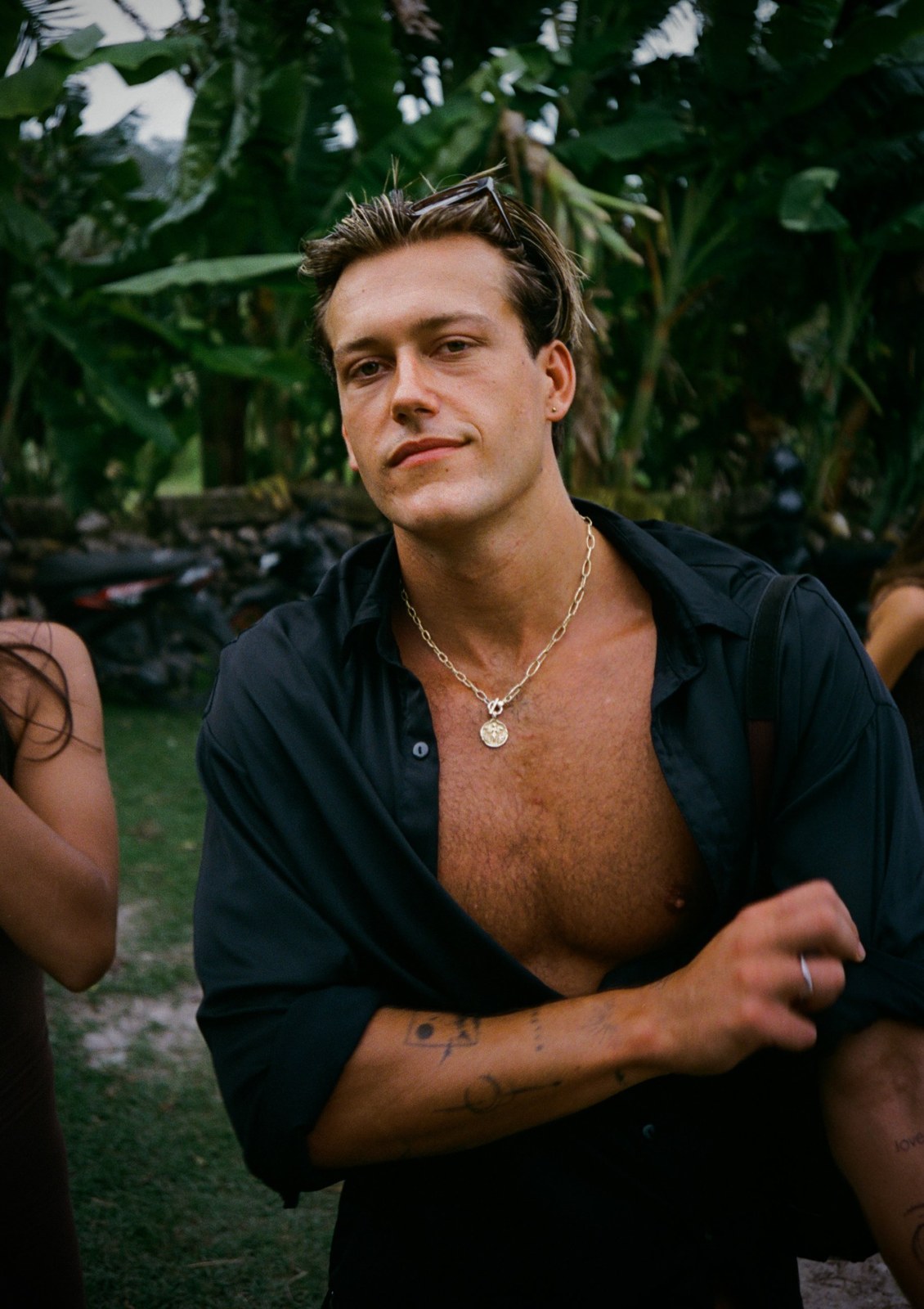 Portrait of Louis Vogler in a black shirt, palm leaves behind him